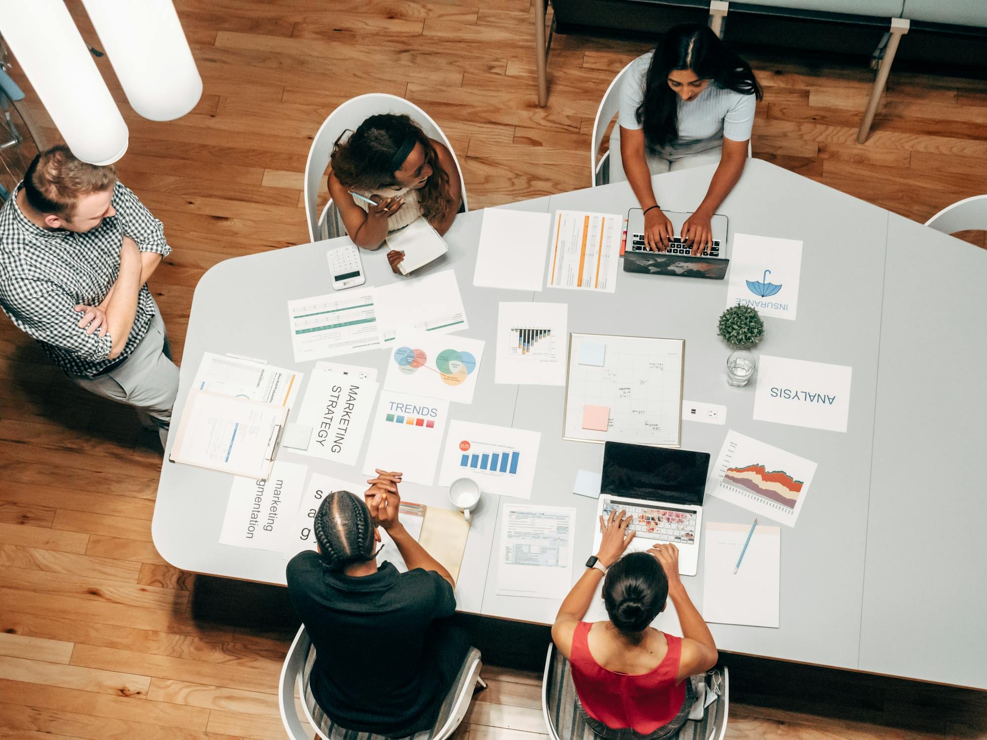 A marketing team mapping strategy across charts and laptops in a modern office.